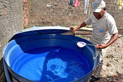 homem aplica substancia em caixa d'água